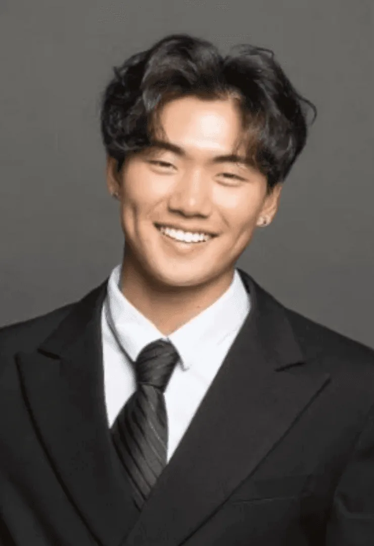 Austin L., Young Guns alumnus and Carnegie Mellon student, smiling in a black suit