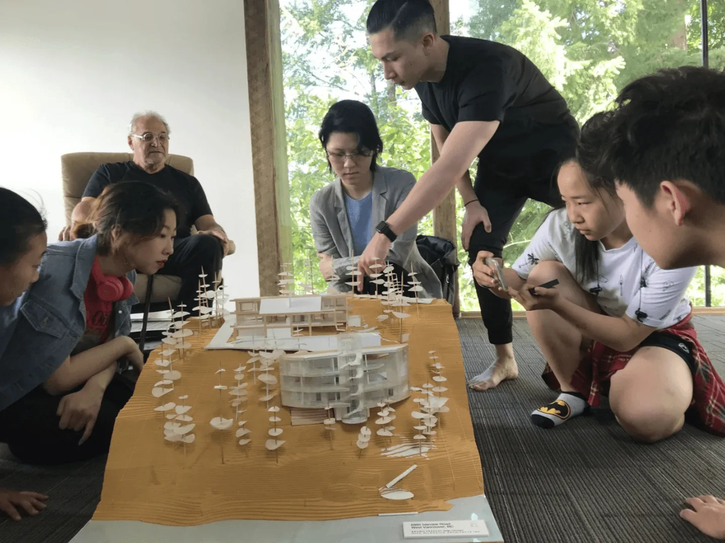 Mentor and students gathered around a detailed architectural model with miniature trees